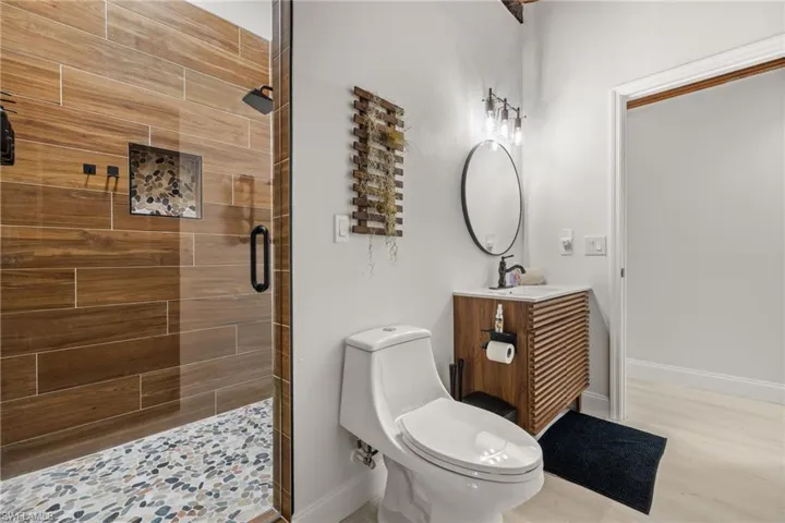 Full bath featuring vanity, a stall shower, and light wood finished floors