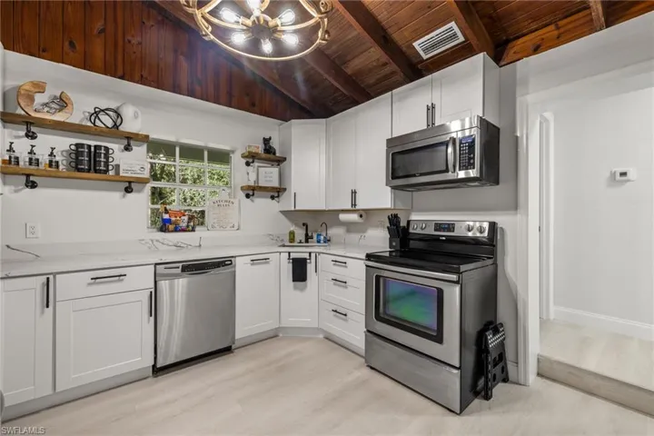 Kitchen featuring open shelves, appliances with stainless steel finishes, white cabinetry, light wood-style floors, and wood ceiling