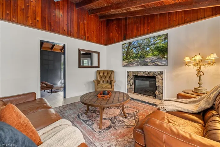 Living room featuring a fireplace, a wooden ceiling with exposed beams, and wood finished floors