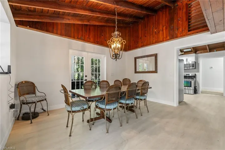 Dining space with french doors, wood ceiling, a chandelier, and light wood finished floors