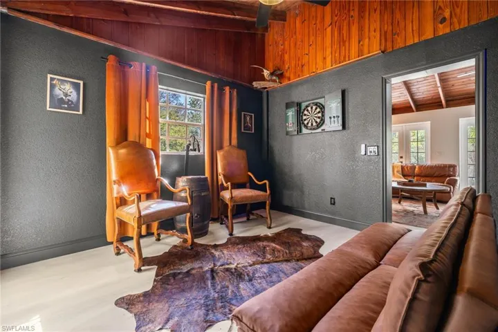 Living area with a textured wall, a wood ceiling with exposed beams, and wood finished floors