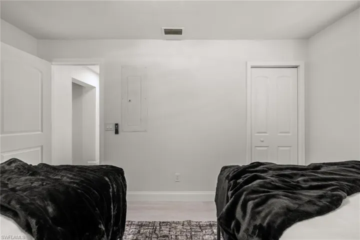 Bedroom featuring electric panel, light wood-type flooring, and a closet