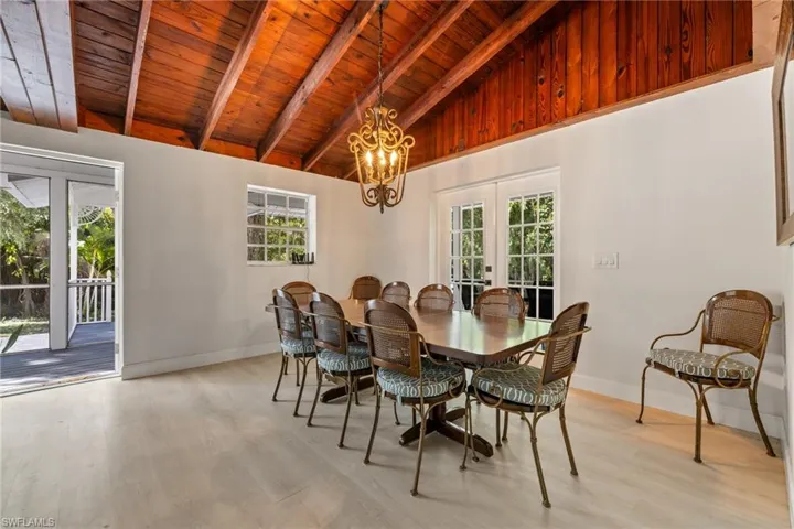 Dining space with french doors, a wooden ceiling with exposed beams, a chandelier, light wood finished floors, and high vaulted ceiling