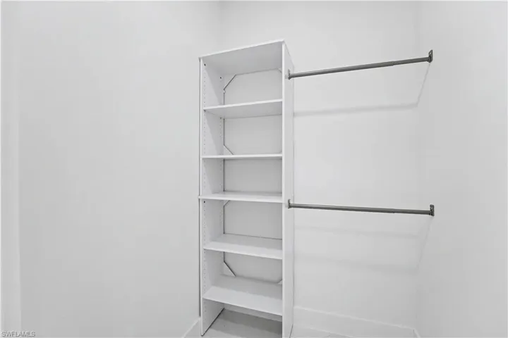 Closet featuring multiple shelves with integrated support brackets and dual hanging rods, offering ample storage and organizational capacity for a range of garments and accessories