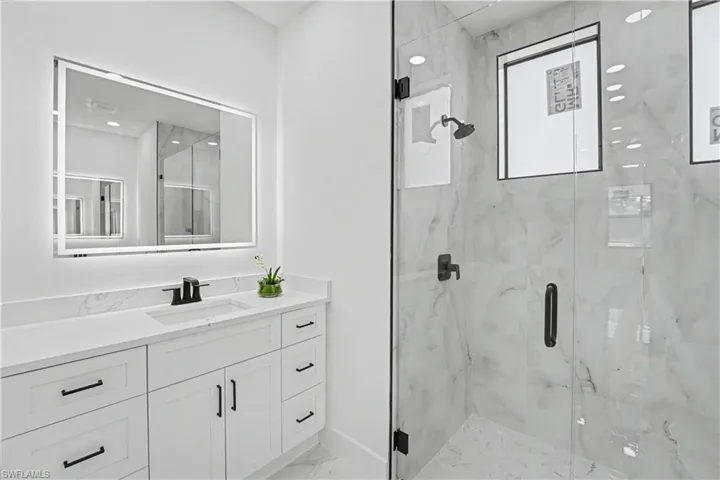 White vanity with black hardware, integrated sink, and white countertop
