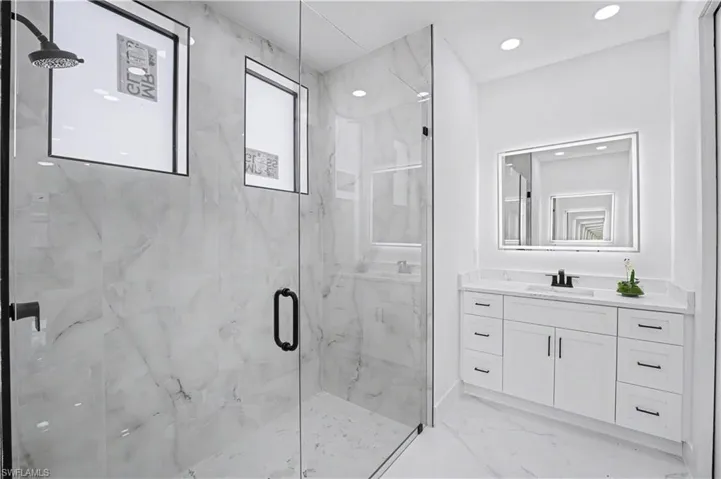 Spacious shower with glass enclosure and rainfall showerhead
