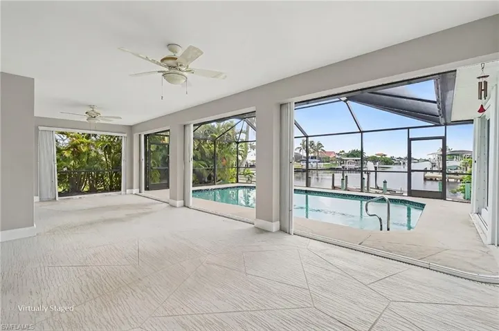Spacious interior with geometric tile flooring, multiple ceiling fans, and expansive screened pool area