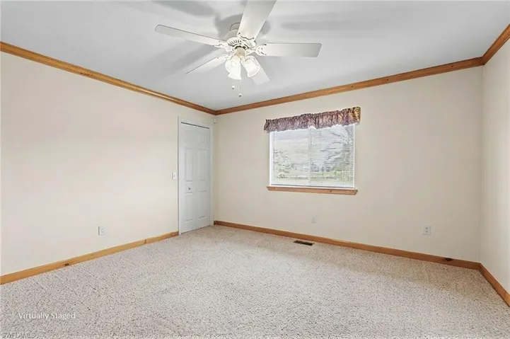 Ceiling fan light fixture, carpet flooring, wall-mounted window, wood trim, and a white interior door