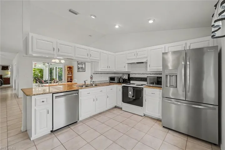 Kitchen featuring white cabinetry, light-toned countertops, stainless steel appliances, and tiled flooring