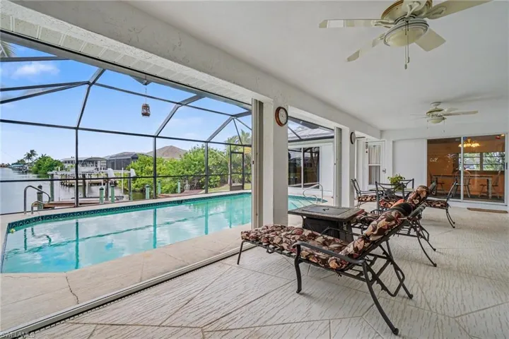 Screened lanai with patterned tile flooring, an integrated swimming pool, and a private dock