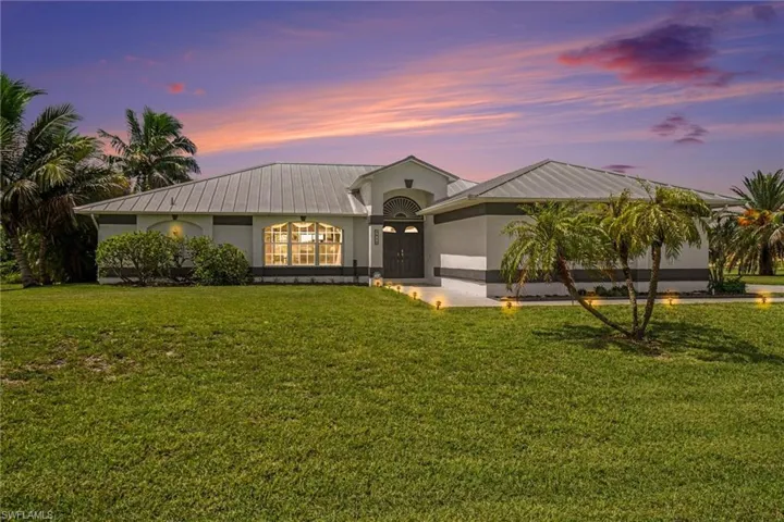 Contemporary exterior with a metal roof, arched transom window, double entry doors, and tropical landscaping