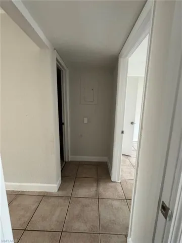 Hall with light tile patterned floors and electric panel