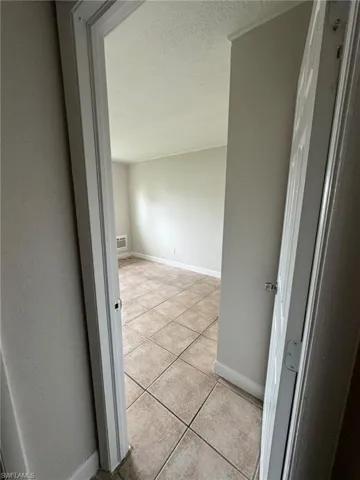 Hallway with a textured ceiling and light tile patterned floors