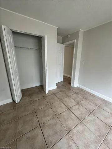Unfurnished bedroom featuring a closet, a textured ceiling, and light tile patterned floors