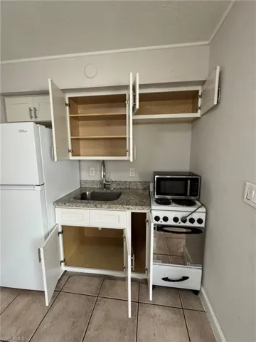 Kitchen featuring open shelves, white appliances, light tile patterned floors, light stone counters, and a textured ceiling