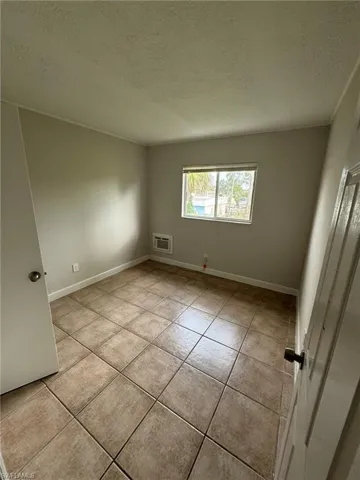 Empty room with a textured ceiling and light tile patterned floors