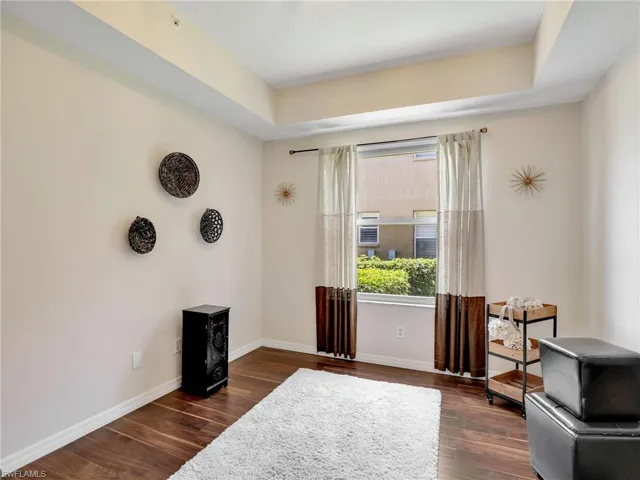 Living area with dark wood-type flooring, baseboards, and a tray ceiling