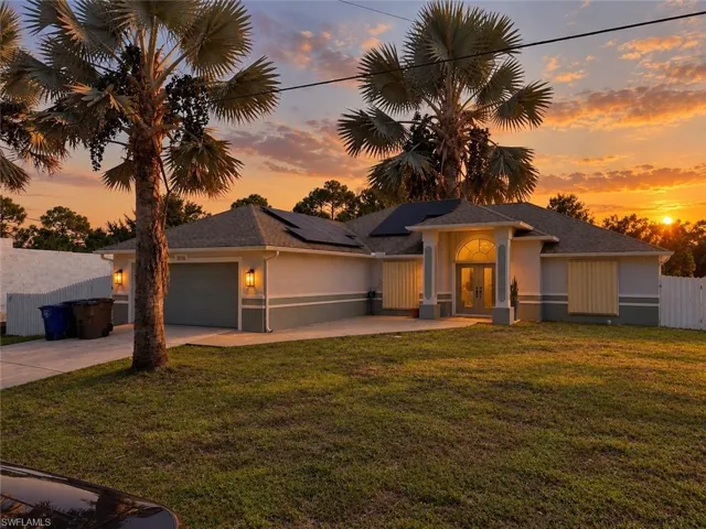 Single-story exterior featuring a hip roof with integrated solar panels, a covered recessed entryway with decorative columns, a multi-pane arched transom window, and a multi-car attached garage