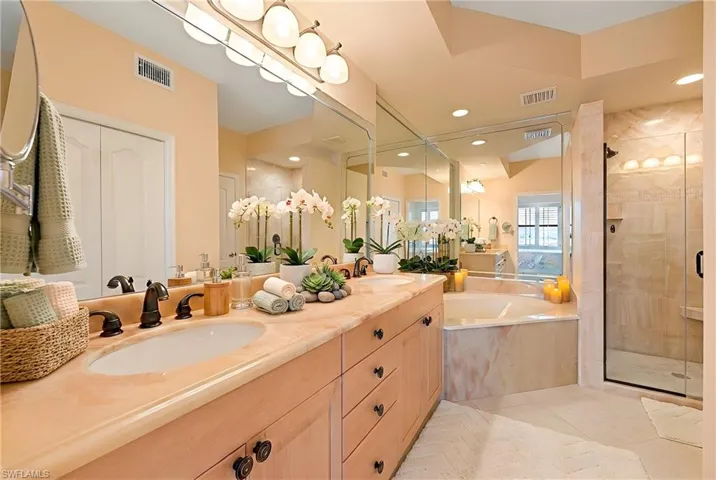 Full bath featuring a stall shower, double vanity, light tile patterned flooring, a bath, and recessed lighting