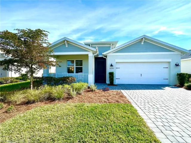View of front of home with a garage, a front lawn, and covered porch