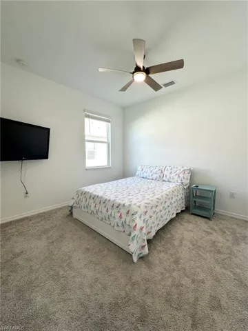 Carpeted bedroom featuring ceiling fan