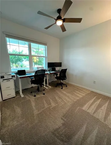 Home office with ceiling fan, a healthy amount of sunlight, and carpet flooring