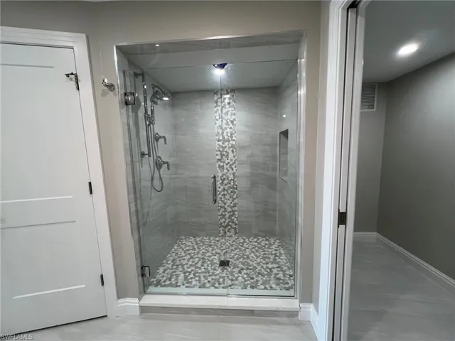 Full bath featuring visible vents, a shower stall, and baseboards