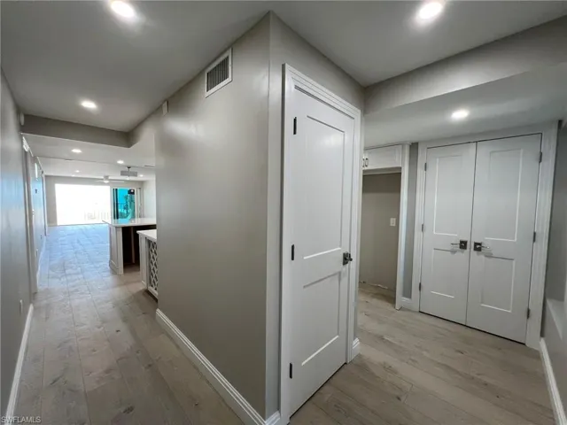 Corridor with light wood-style flooring, recessed lighting, visible vents, and baseboards