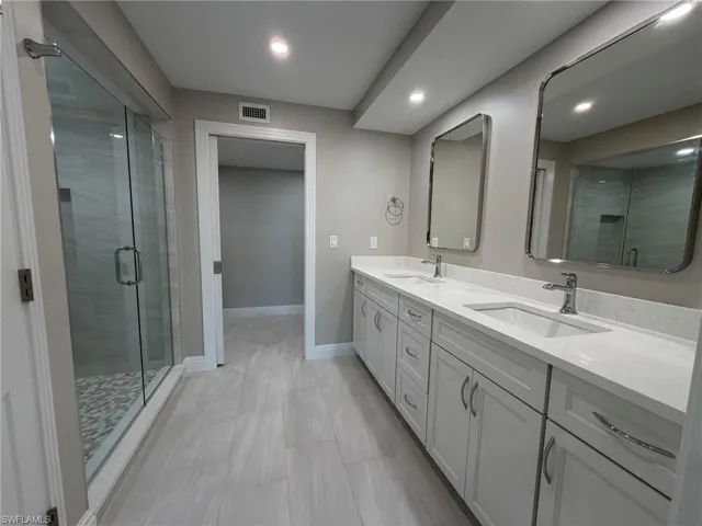 Bathroom featuring double vanity, a shower stall, and recessed lighting