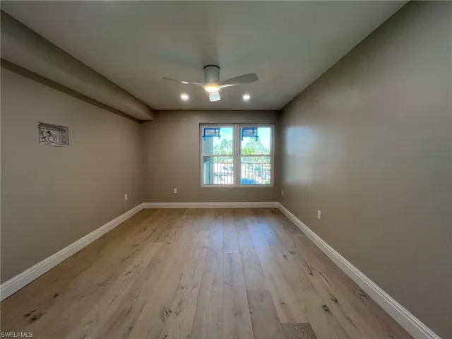 Spare room with a ceiling fan, light wood-style floors, and baseboards