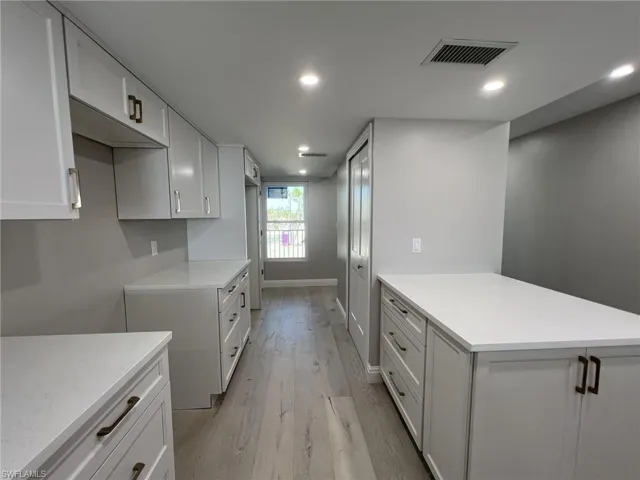 Kitchen with visible vents, light wood finished floors, baseboards, a peninsula, and recessed lighting