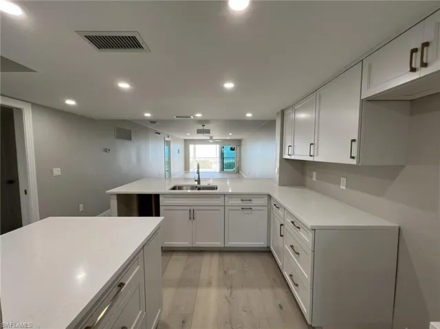 Kitchen with a sink, visible vents, light wood finished floors, and light countertops