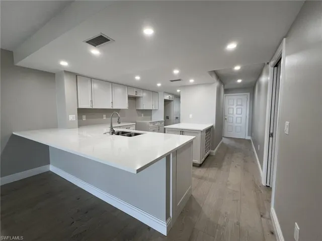 Kitchen featuring visible vents, a sink, wood finished floors, recessed lighting, and a peninsula