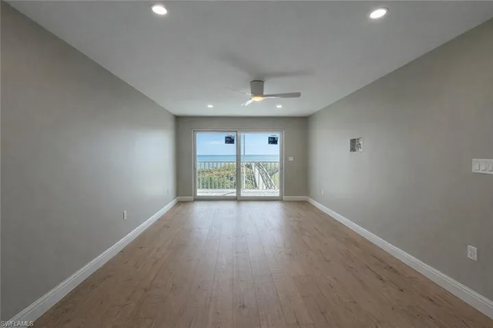 Unfurnished room featuring light wood-style flooring, a ceiling fan, recessed lighting, and a water view