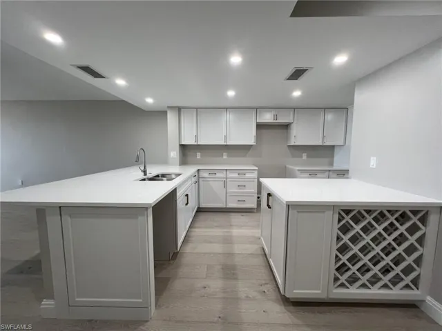 Kitchen featuring light wood finished floors, visible vents, a peninsula, and a sink