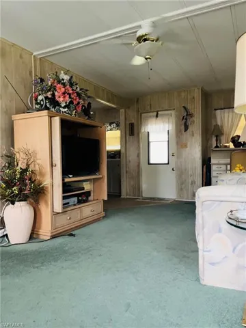 Unfurnished living room featuring wooden walls and carpet floors