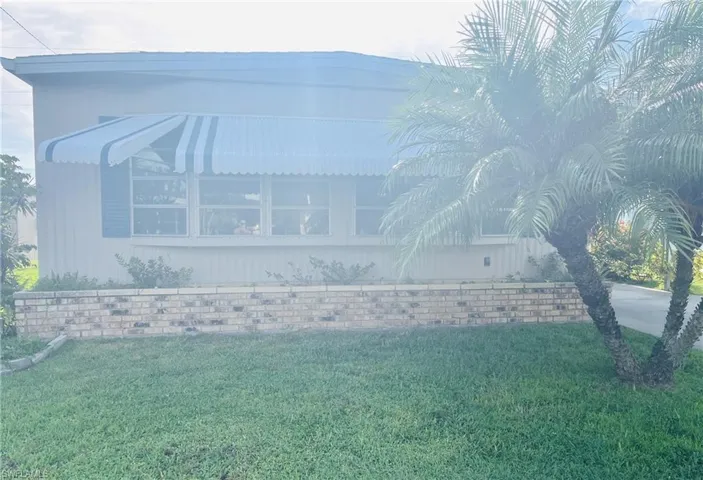 Manufactured / mobile home with a carport, a front yard, and concrete driveway