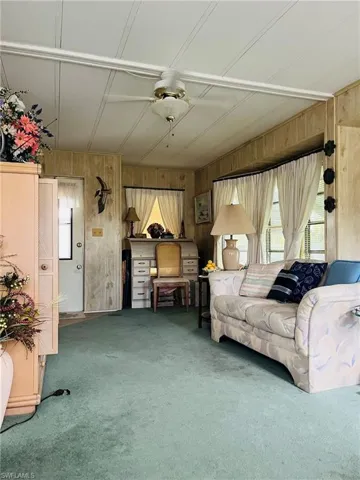 Unfurnished living room featuring wooden walls and carpet