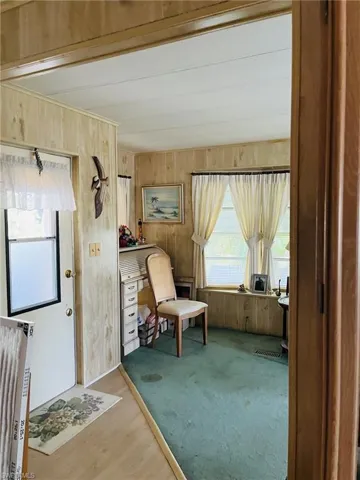 Living room with a ceiling fan, wooden walls, and carpet