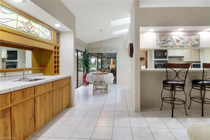 Kitchen featuring lofted ceiling, a skylight, black appliances, recessed lighting, and light tile patterned floors
