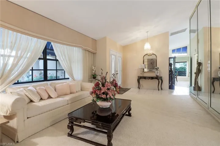 Carpeted living room featuring lofted ceiling and a chandelier