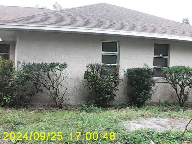 View of side of home with a shingled roof and stucco siding