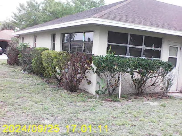 View of property exterior featuring stucco siding, roof with shingles, and a lawn