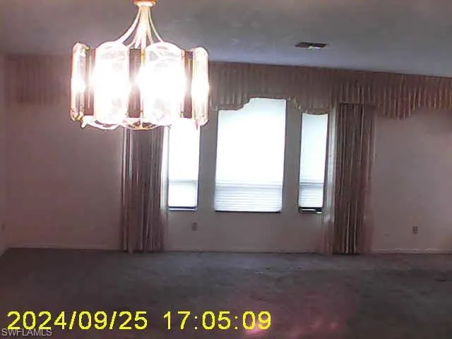 Unfurnished dining area with hanging lights and dark carpet