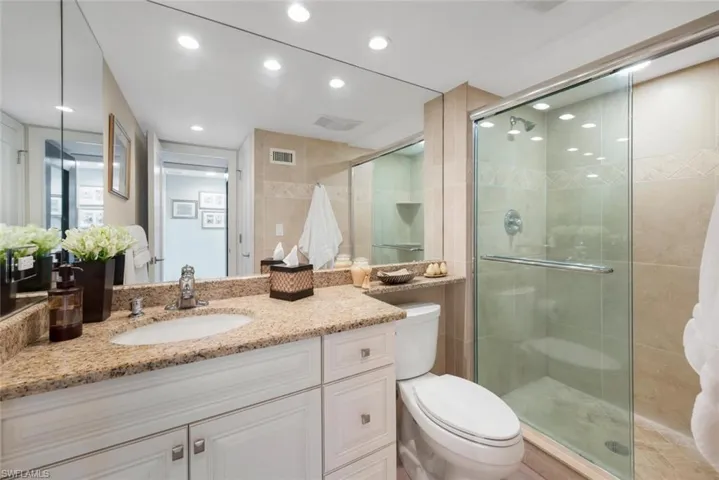 Bathroom with a shower with door, large vanity, and toilet