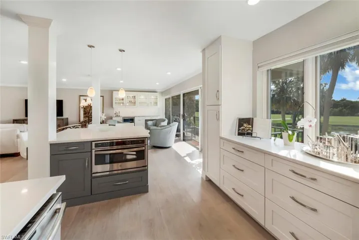 Kitchen with decorative light fixtures, white cabinetry, light wood-type flooring, gray cabinets, and appliances with stainless steel finishes