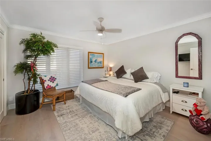 Bedroom with wood-type flooring, ceiling fan, and crown molding