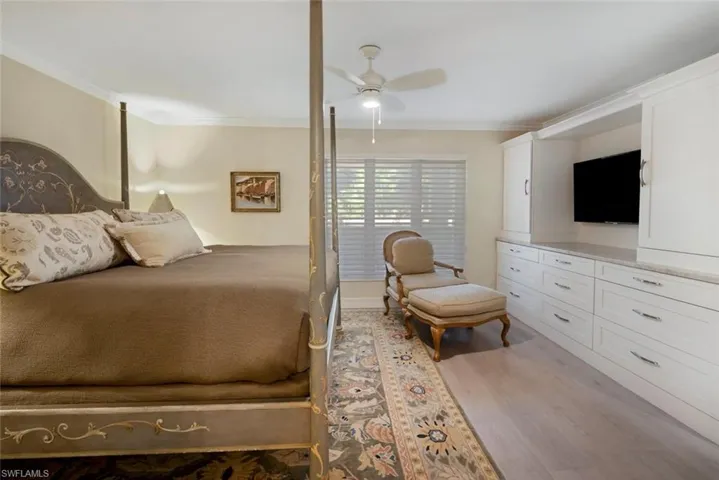 Bedroom with wood-type flooring, ceiling fan, and crown molding