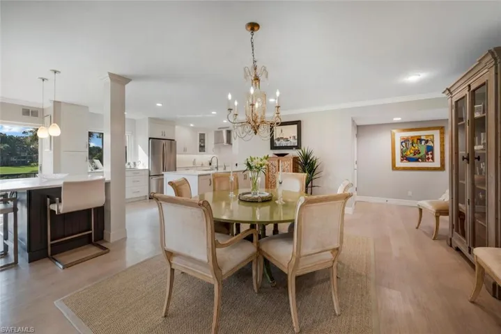 Dining area with a notable chandelier, sink, light hardwood / wood-style flooring, and crown molding