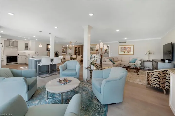 Living room with sink, ornamental molding, light hardwood / wood-style flooring, and decorative columns
